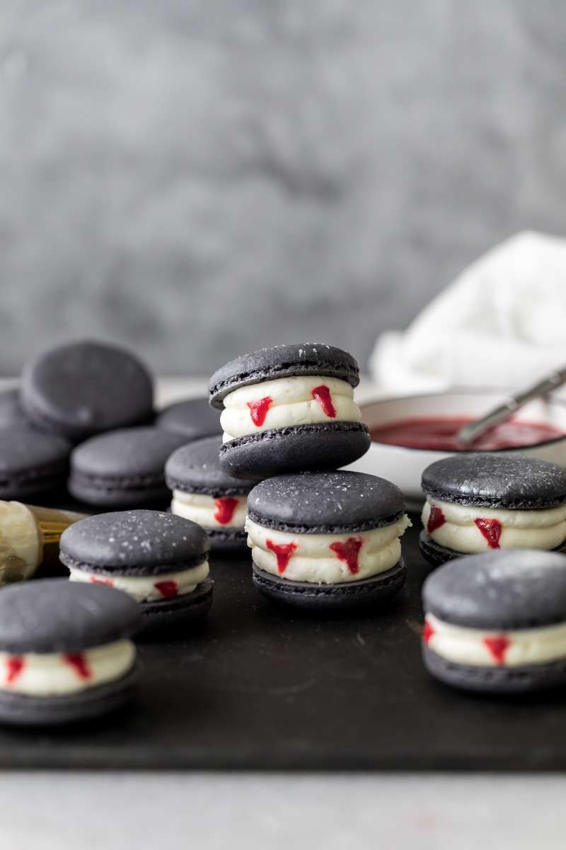 Easy Vampire decorated macarons for Halloween, with black cocoa shells, vanilla bean frosting and strawberry jam. A spooky sweet macaron for the fall season! Dairy free & Gluten free