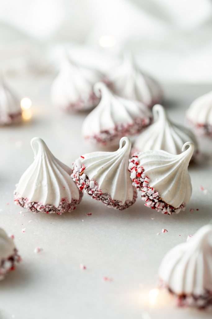 Chocolate dipped peppermint meringue cookies topped with crushed candy canes for Christmas.