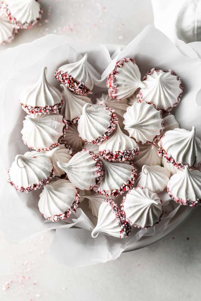 Chocolate dipped peppermint meringue cookies topped with crushed candy canes for Christmas.