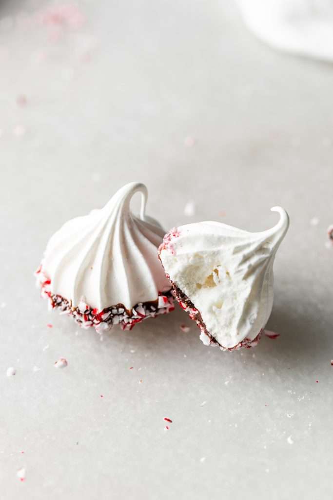 Chocolate dipped peppermint meringue cookies topped with crushed candy canes for Christmas.