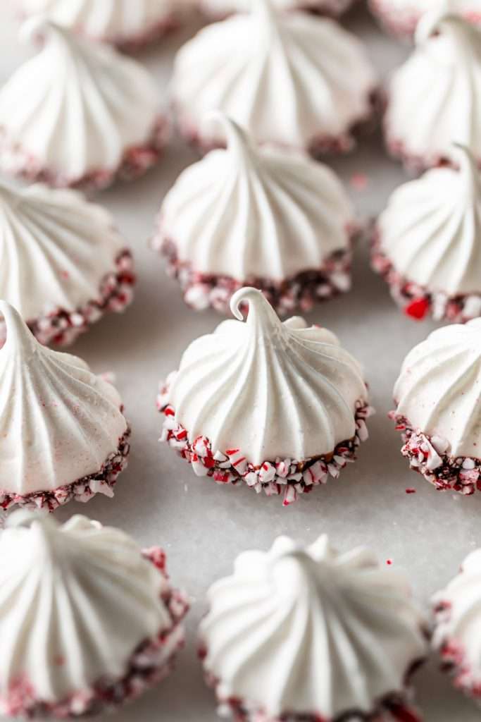 Chocolate dipped peppermint meringue cookies topped with crushed candy canes for Christmas.