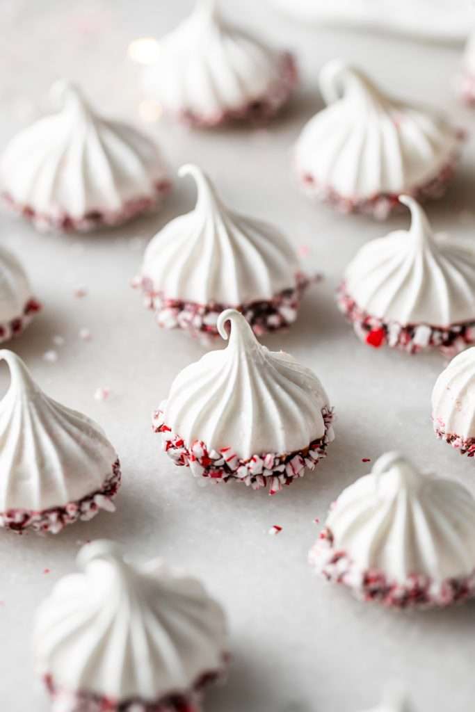 Chocolate dipped peppermint meringue cookies topped with crushed candy canes for Christmas.