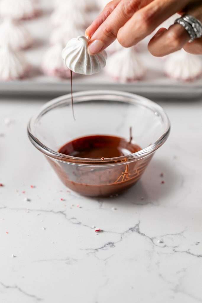 Chocolate dipped peppermint meringue cookies topped with crushed candy canes for Christmas.