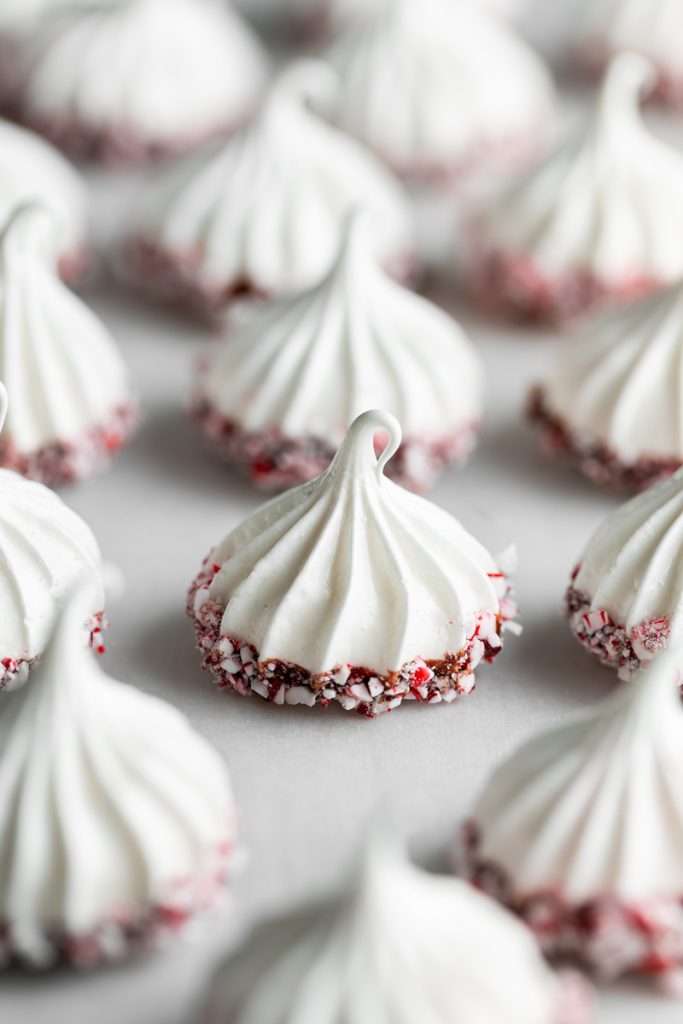 Chocolate dipped peppermint meringue cookies topped with crushed candy canes for Christmas.
