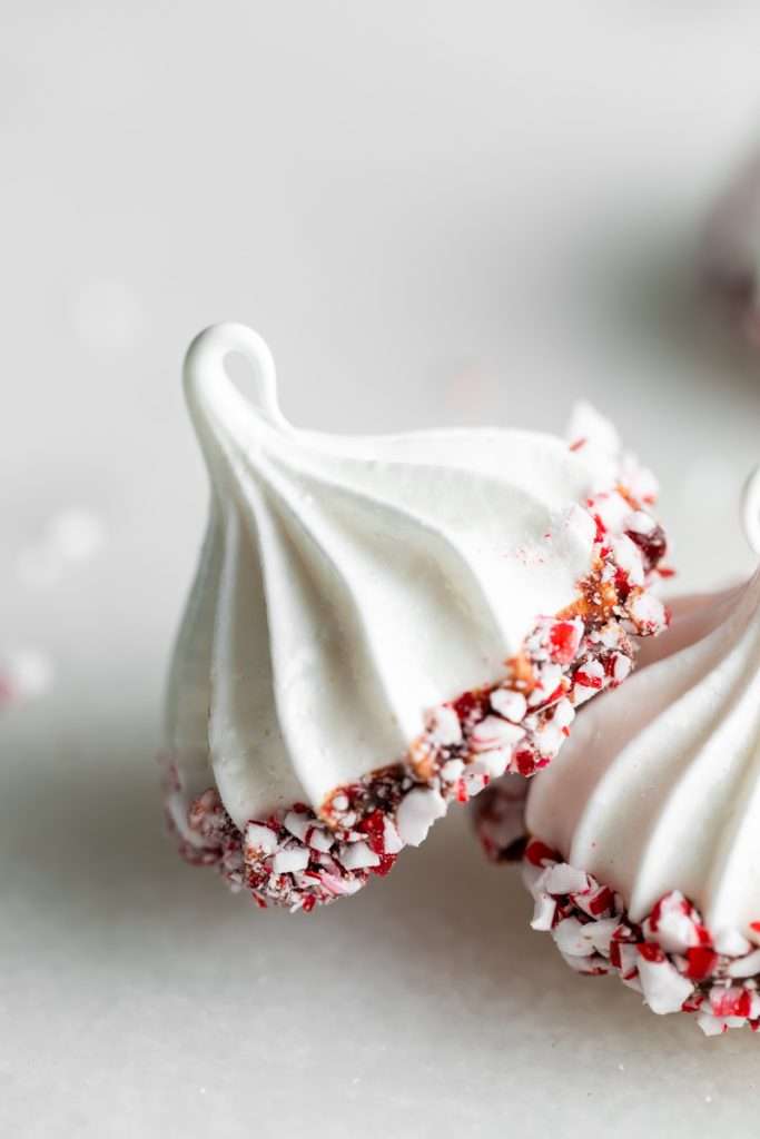Chocolate dipped peppermint meringue cookies topped with crushed candy canes for Christmas.