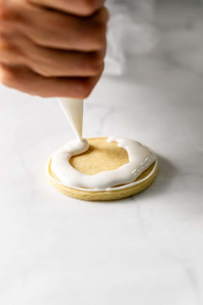 Winter themed roll out sugar cookies, flooded with a royal icing base and decorated with easy three dimension trees and snowmen, using star and round piping tips. The Christmas cookie design requires little decorating experience and will be perfect for your next holiday party or cookie exchange! 