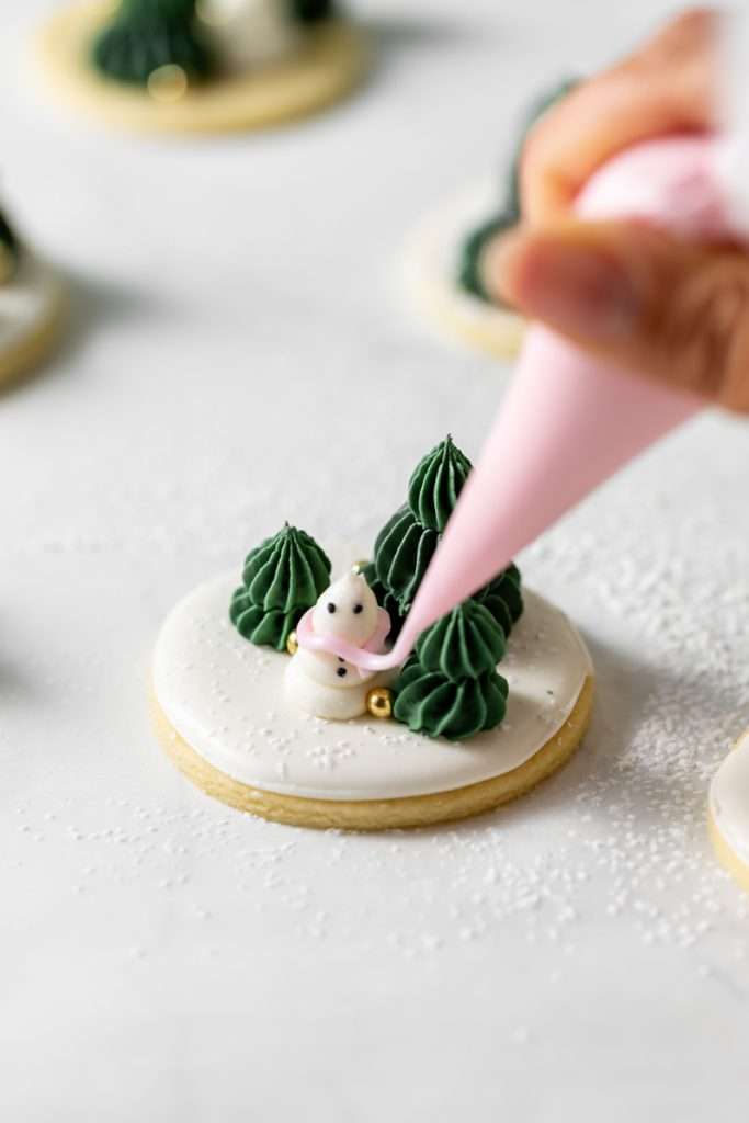 Winter themed roll out sugar cookies, flooded with a royal icing base and decorated with easy three dimension trees and snowmen, using star and round piping tips. The Christmas cookie design requires little decorating experience and will be perfect for your next holiday party or cookie exchange! 