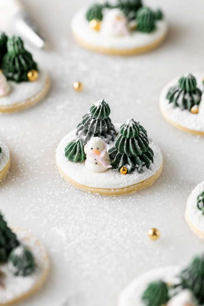 Winter themed roll out sugar cookies, flooded with a royal icing base and decorated with easy three dimension trees and snowmen, using star and round piping tips. The Christmas cookie design requires little decorating experience and will be perfect for your next holiday party or cookie exchange! 