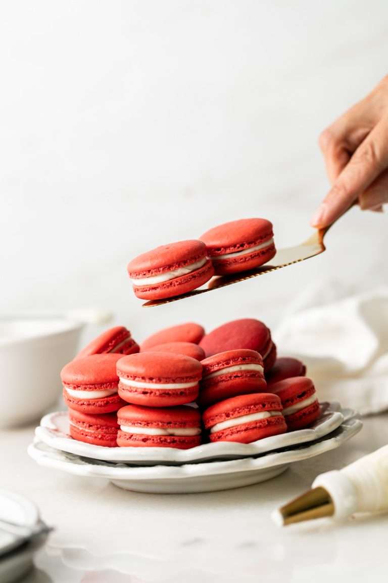 Red velvet macarons inspired by the classic cake, featuring cocoa infused shells tinted red, cream cheese frosting, with red velvet infused chocolate ganache. The perfect treat for Valentine's Day and red velvet cake lovers!