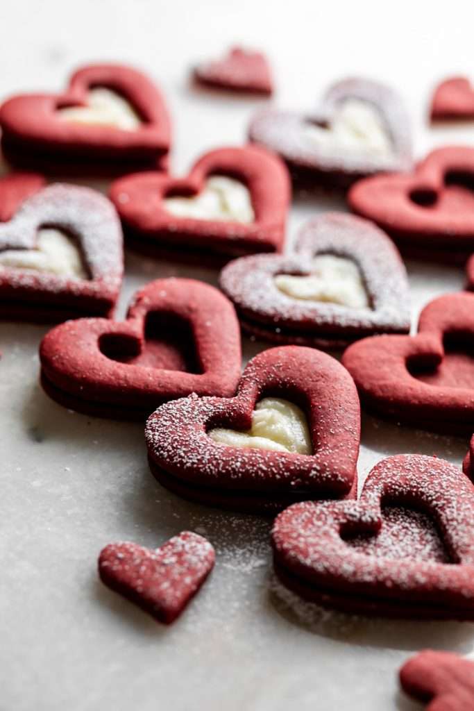 Easy red velvet Linzer cookies, with a hint of cocoa, and tangy cream cheese frosting. These cookies ca be cut into any shape and are the perfect treat for any occasion from Valentine's Day to Christmas.
