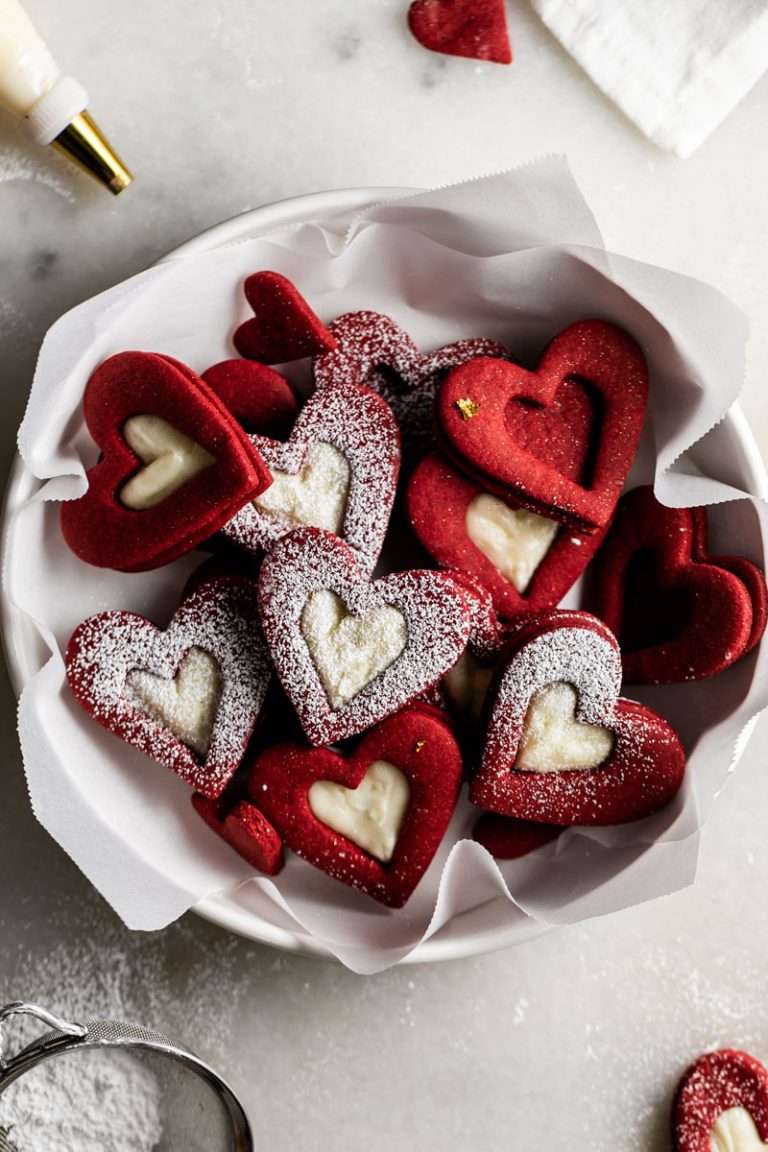 Easy red velvet Linzer cookies, with a hint of cocoa, and tangy cream cheese frosting. These cookies ca be cut into any shape and are the perfect treat for any occasion from Valentine's Day to Christmas.