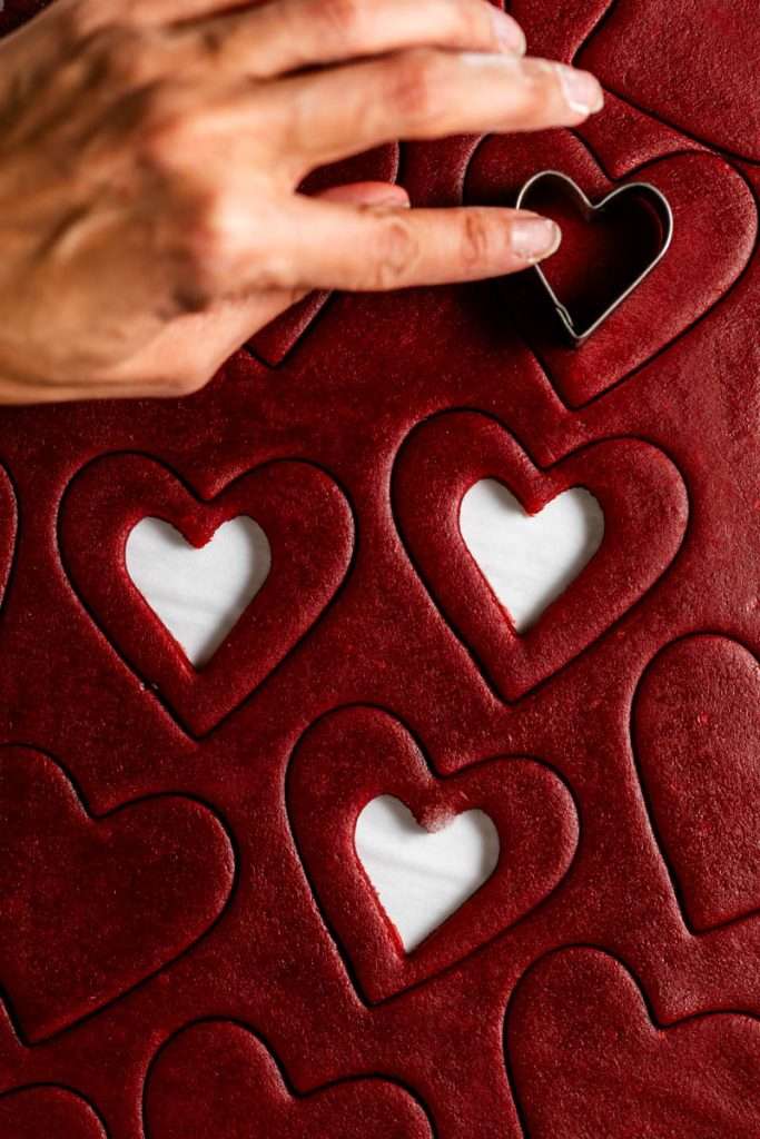 Easy red velvet Linzer cookies, with a hint of cocoa, and tangy cream cheese frosting. These cookies ca be cut into any shape and are the perfect treat for any occasion from Valentine's Day to Christmas.
