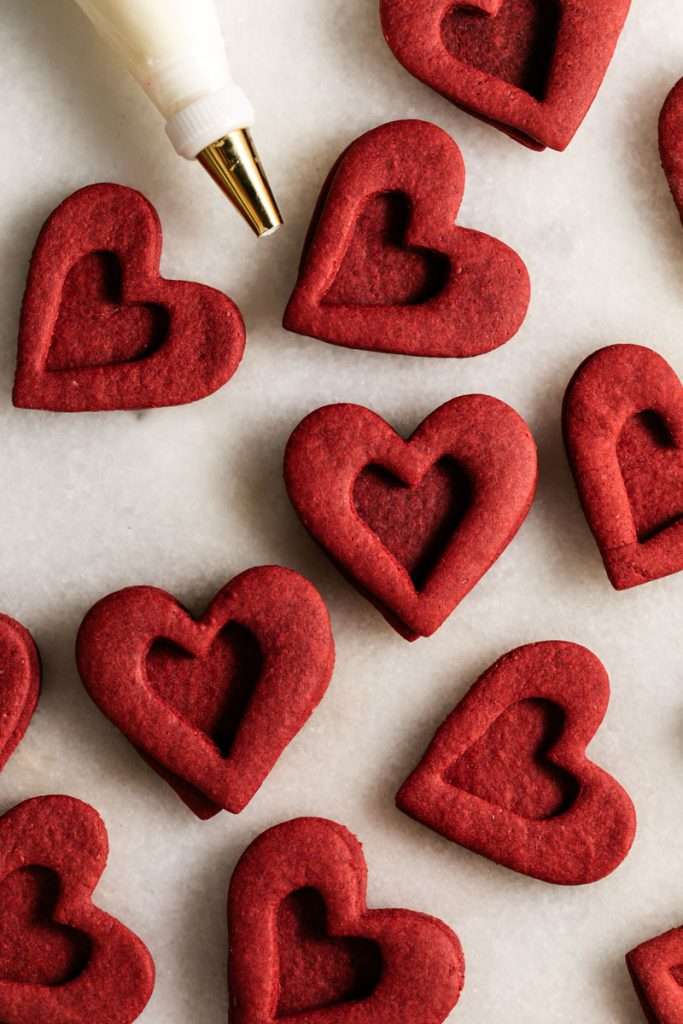 Easy red velvet Linzer cookies, with a hint of cocoa, and tangy cream cheese frosting. These cookies ca be cut into any shape and are the perfect treat for any occasion from Valentine's Day to Christmas.