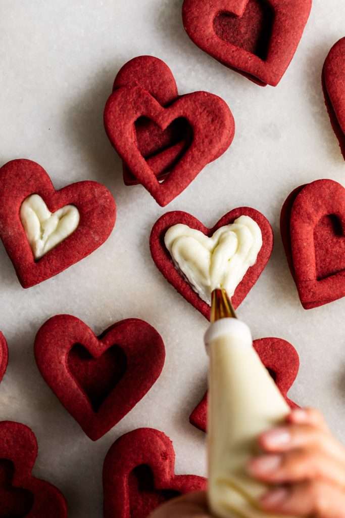 Easy red velvet Linzer cookies, with a hint of cocoa, and tangy cream cheese frosting. These cookies ca be cut into any shape and are the perfect treat for any occasion from Valentine's Day to Christmas.