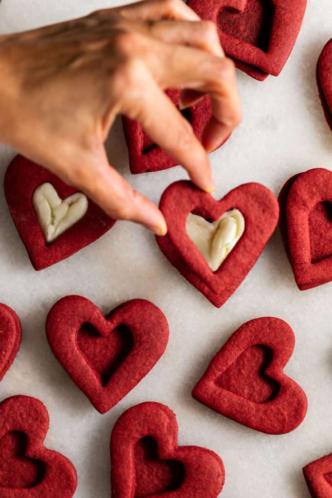 Easy red velvet Linzer cookies, with a hint of cocoa, and tangy cream cheese frosting. These cookies ca be cut into any shape and are the perfect treat for any occasion from Valentine's Day to Christmas.