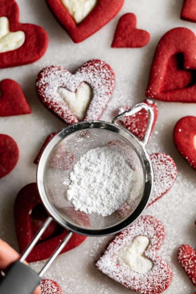 Easy red velvet Linzer cookies, with a hint of cocoa, and tangy cream cheese frosting. These cookies ca be cut into any shape and are the perfect treat for any occasion from Valentine's Day to Christmas.