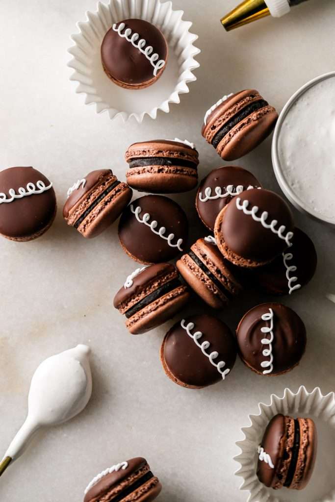 Hostess cupcake inspired macarons, with rich dark chocolate frosting and fluffy marshmallow filling. The shells are dipped in dark chocolate and decorated with icing loops to complete the look and taste! Check out the recipe, video and step by step instructions. Dairy free and gluten free option.