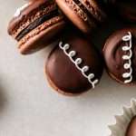 Hostess cupcake macarons recipe, a play on the original, filled with rich dark chocolate frosting and fluffy marshmallow filling. The shells are dipped in dark chocolate and decorated with icing loops to complete the look and taste! Check out the recipe, video and step by step instructions. Dairy free and gluten free option.