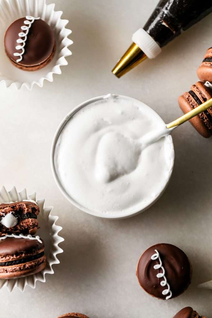 Hostess cupcake inspired macarons, with rich dark chocolate frosting and fluffy marshmallow filling. The shells are dipped in dark chocolate and decorated with icing loops to complete the look and taste! Check out the recipe, video and step by step instructions. Dairy free and gluten free option.
