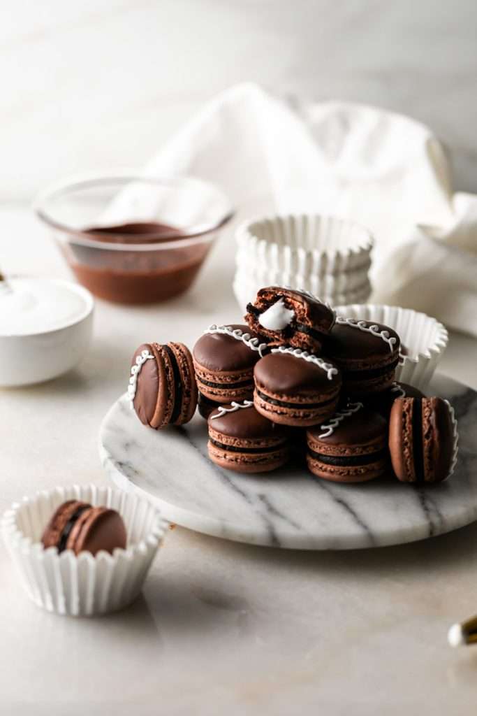 Hostess cupcake inspired macarons, with rich dark chocolate frosting and fluffy marshmallow filling. The shells are dipped in dark chocolate and decorated with icing loops to complete the look and taste! Check out the recipe, video and step by step instructions. Dairy free and gluten free option.
