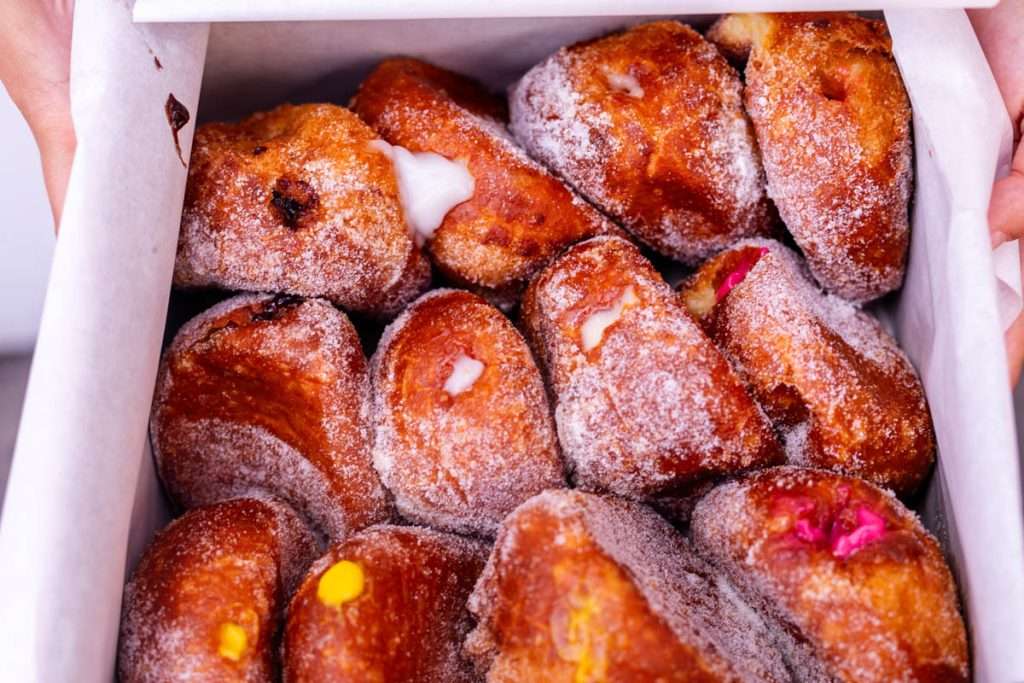 Fresh baked malasadas from Leonard's Bakery in Honolulu Hawaii, Oahu. Lilikoi, Coconut, Chocolate, Guava, fried dough covered in sugar.