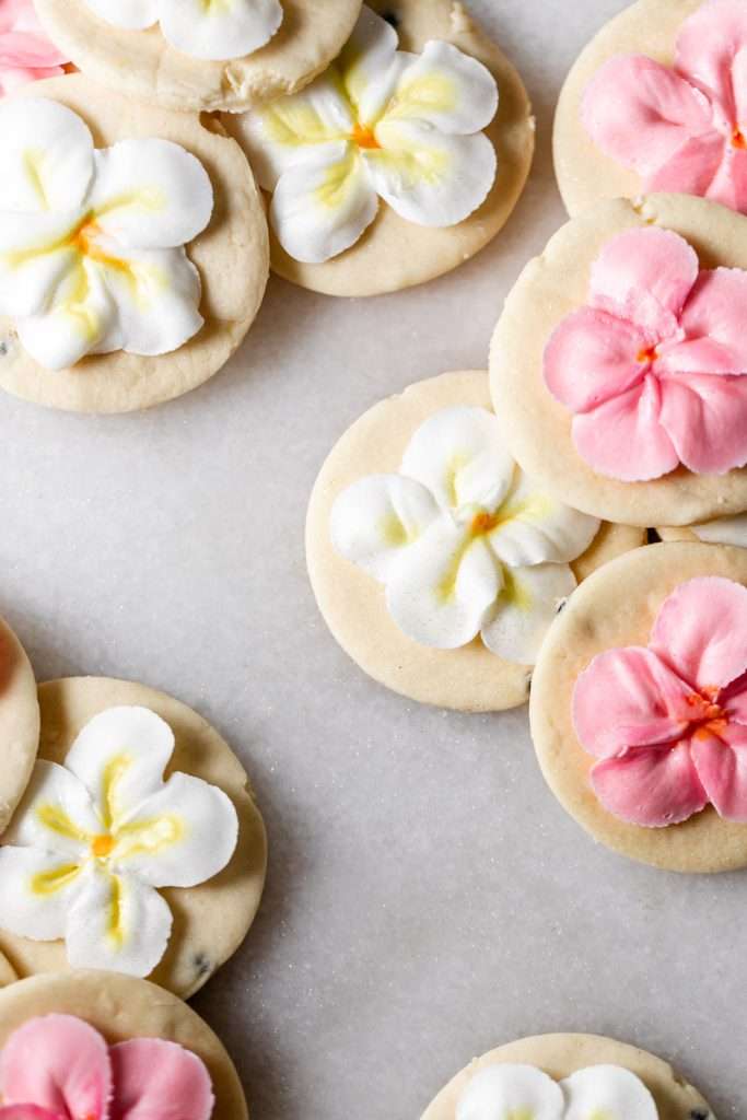 Recipe for tropical sugar cookies, infused with fresh passion fruit and decorated with plumeria royal icing transfers. Step by step instructions and video included.