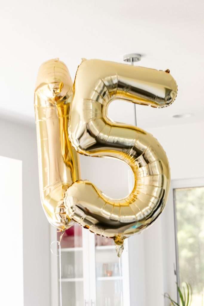 Number fifteen soft golden balloons for flower themed teen birthday party