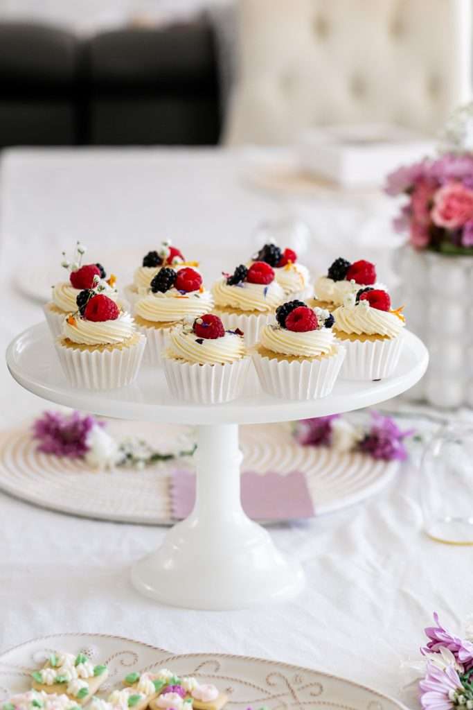 Vanilla cupcakes with fresh berries and flower garnish for - Flower themed teen Birthday party. Table decor