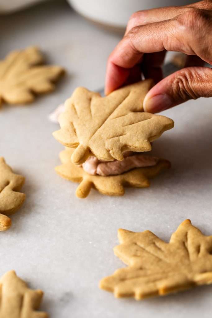 Easy and delicious maple leaf cookies, inspired by Canadian maple cookies filled with maple buttercream and simply decorated with edible gold. A wonderful treat for the fall season and for upcoming fall gatherings. Dairy free option included.