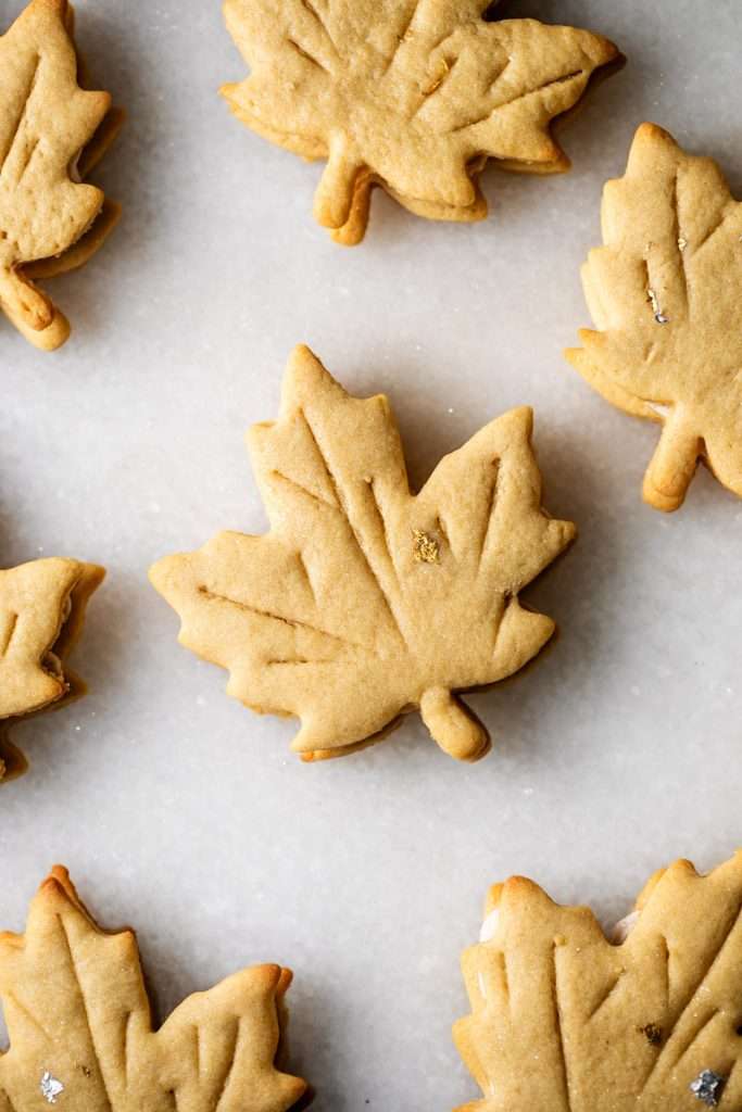 Easy and delicious maple leaf cookies, inspired by Canadian maple cookies filled with maple buttercream and simply decorated with edible gold. A wonderful treat for the fall season and for upcoming fall gatherings. Dairy free option included.