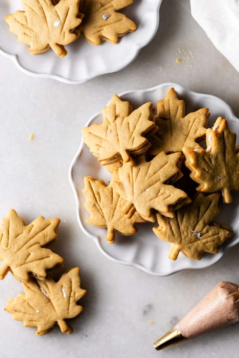 Easy and delicious maple leaf cookies, inspired by Canadian maple cookies filled with maple buttercream and simply decorated with edible gold. A wonderful treat for the fall season and for upcoming fall gatherings. Dairy free option included.