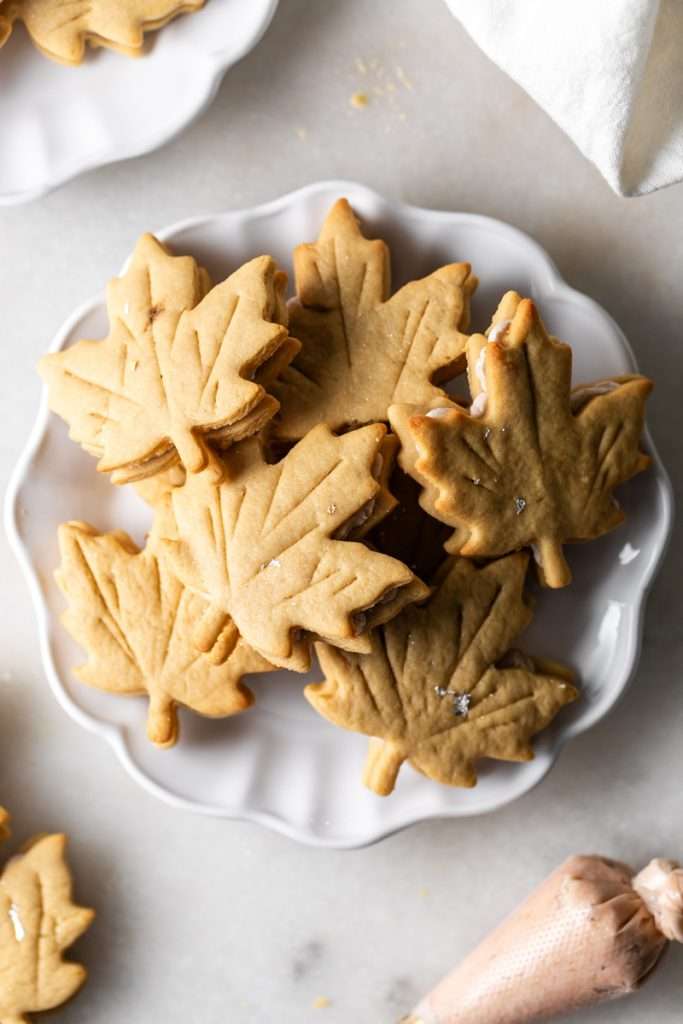 Easy and delicious maple leaf cookies, inspired by Canadian maple cookies filled with maple buttercream and simply decorated with edible gold. A wonderful treat for the fall season and for upcoming fall gatherings. Dairy free option included.