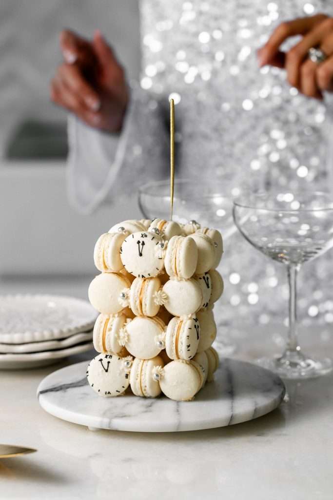 New Years Eve Macaron Cube Cake stacked with 36 biscoff ganache filled shells and decorated with royal icing clocks. A festive and fitting treat to for the new year ahead.