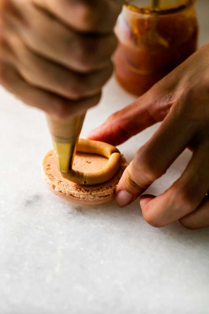 Almond Apricot Macarons filled with almond flavored ganache and apricot preserves. An effortless and delicious macaron flavor for the spring and summer season. Recipe is dairy free and gluten free.