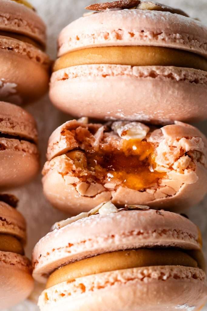 Almond Apricot Macarons filled with almond flavored ganache and apricot preserves. An effortless and delicious macaron flavor for the spring and summer season. Recipe is dairy free and gluten free.