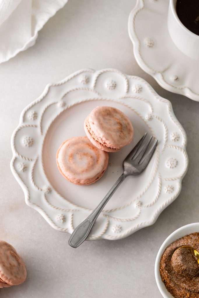 Cinnamon roll flavored macarons for breakfast and brunch. The swirled shells are filled with cinnamon roll white chocolate ganache and topped with icing for the ultimate cinnamon roll flavor. A gluten free recipe.