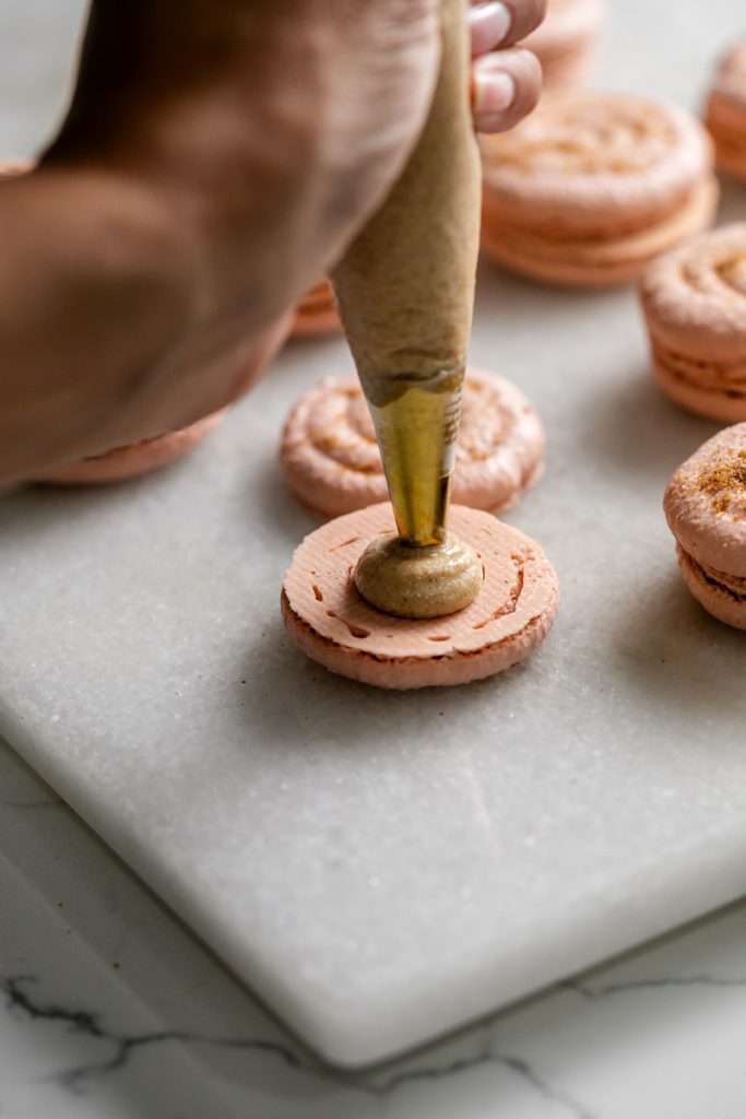 Cinnamon roll flavored macarons for breakfast and brunch. The swirled shells are filled with cinnamon roll white chocolate ganache and topped with icing for the ultimate cinnamon roll flavor. A gluten free recipe.