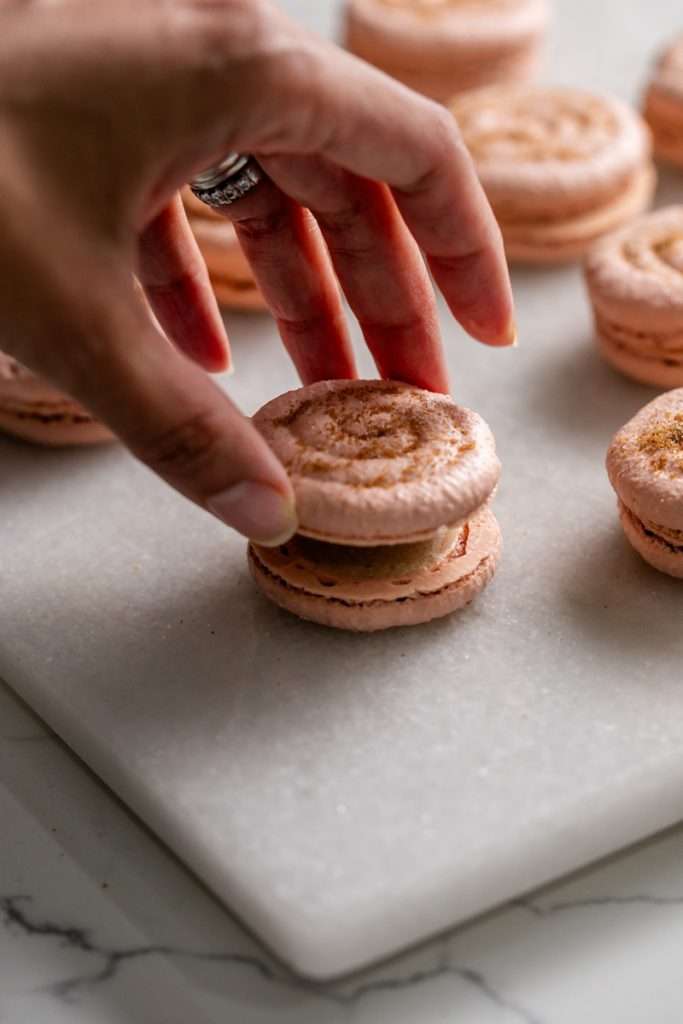 Cinnamon roll flavored macarons for breakfast and brunch. The swirled shells are filled with cinnamon roll white chocolate ganache and topped with icing for the ultimate cinnamon roll flavor. A gluten free recipe.