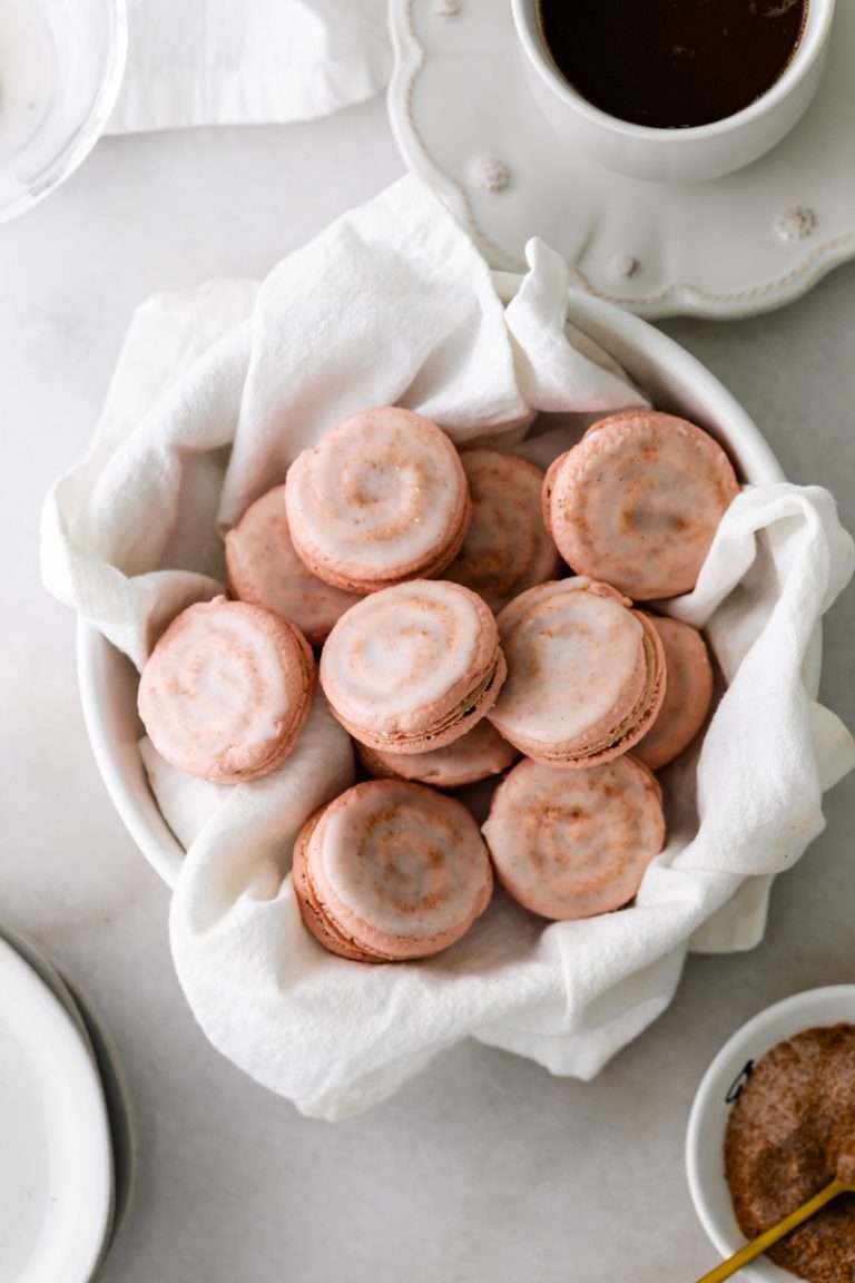 Cinnamon roll flavored macarons for breakfast and brunch. The swirled shells are filled with cinnamon roll white chocolate ganache and topped with icing for the ultimate cinnamon roll flavor. A gluten free recipe.