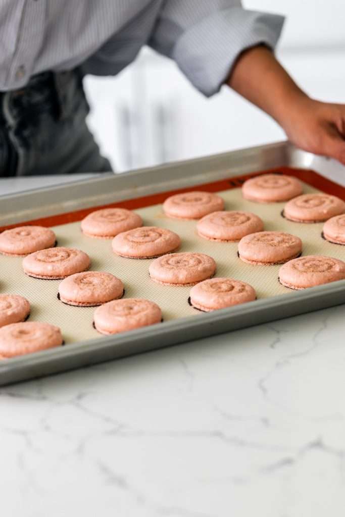 Cinnamon roll flavored macarons for breakfast and brunch. The swirled shells are filled with cinnamon roll white chocolate ganache and topped with icing for the ultimate cinnamon roll flavor. A gluten free recipe.