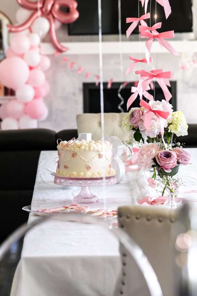 Pink coquette and bow themed birthday party sweets, including cake, and sugar cookies with royal icing.