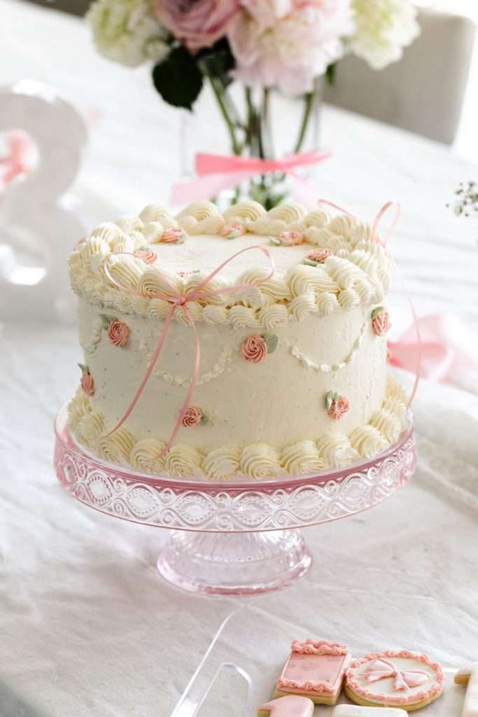 Homemade vintage inspired birthday cake with rosettes and scalloped lambeth piped details.