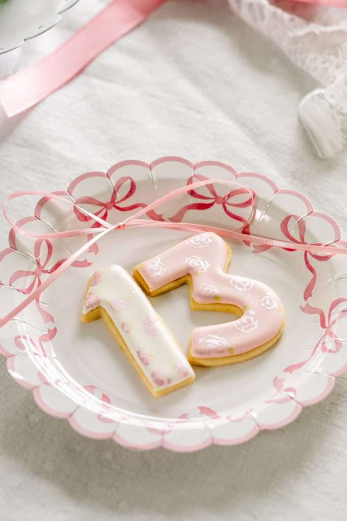 Pink coquette and bow themed custom sugar cookies with royal icing for teen birthday parties. Dessert ideas.
