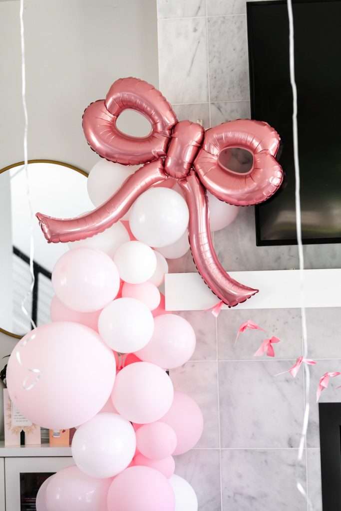 Coquette bow themed pink balloon garland for teen birthday party.