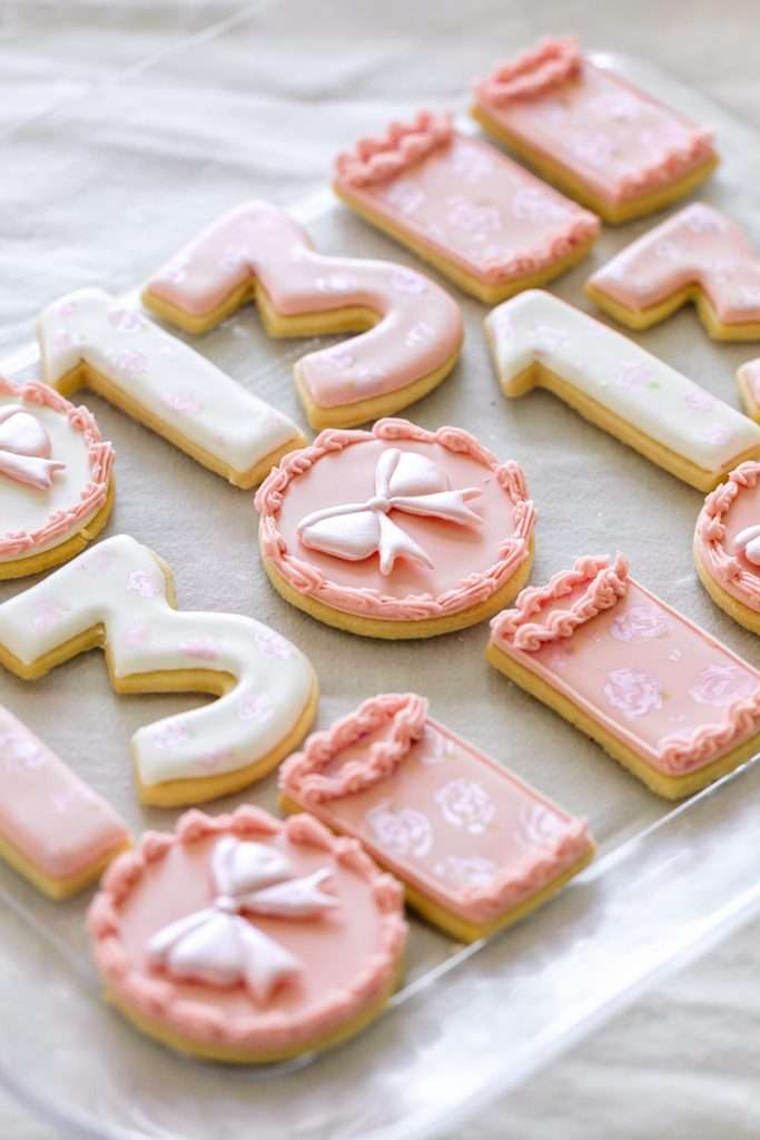 Pink coquette and bow themed custom sugar cookies with royal icing for teen birthday parties. Dessert ideas.
