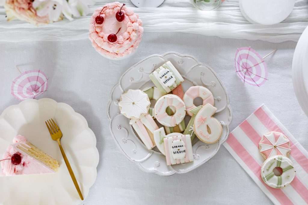 Cabana themed party desserts with custom sugar cookies and homemade pink lambeth cakes.