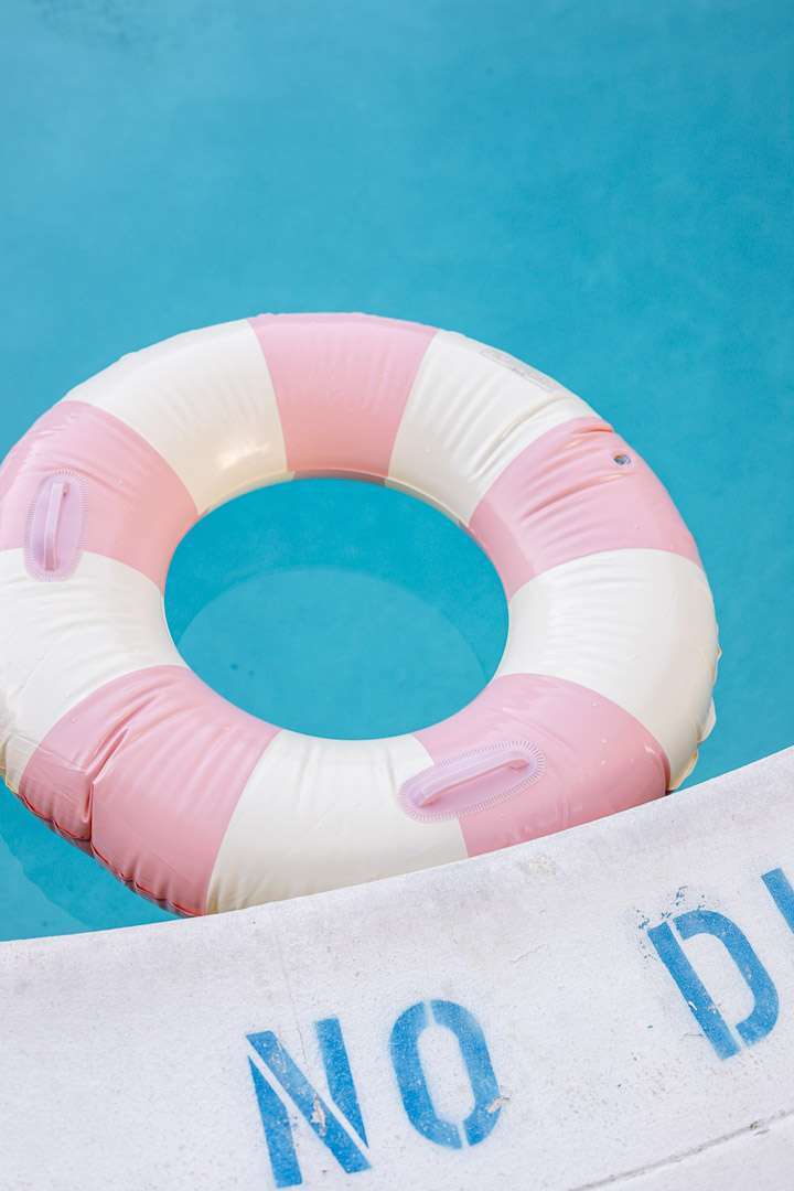 Pink and white striped pool floats for teen cabana themed pool party.