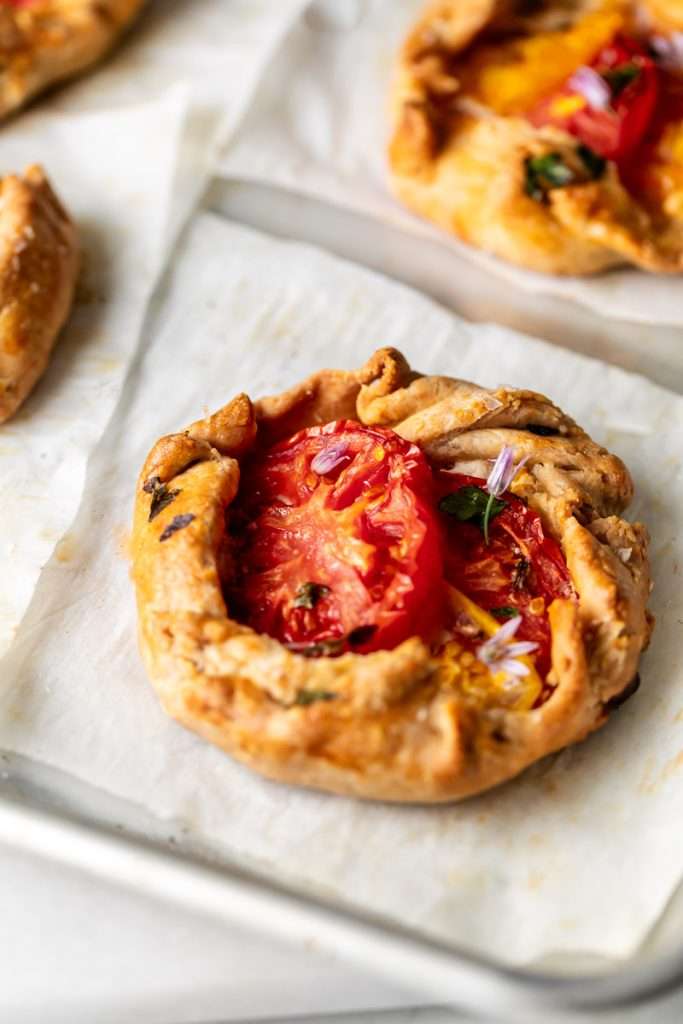 Mini tomato galettes, the perfect party appetizer or brunch treat! Flaky pastry, creamy goat cheese and fresh garden tomatoes, and baked until golden brown.