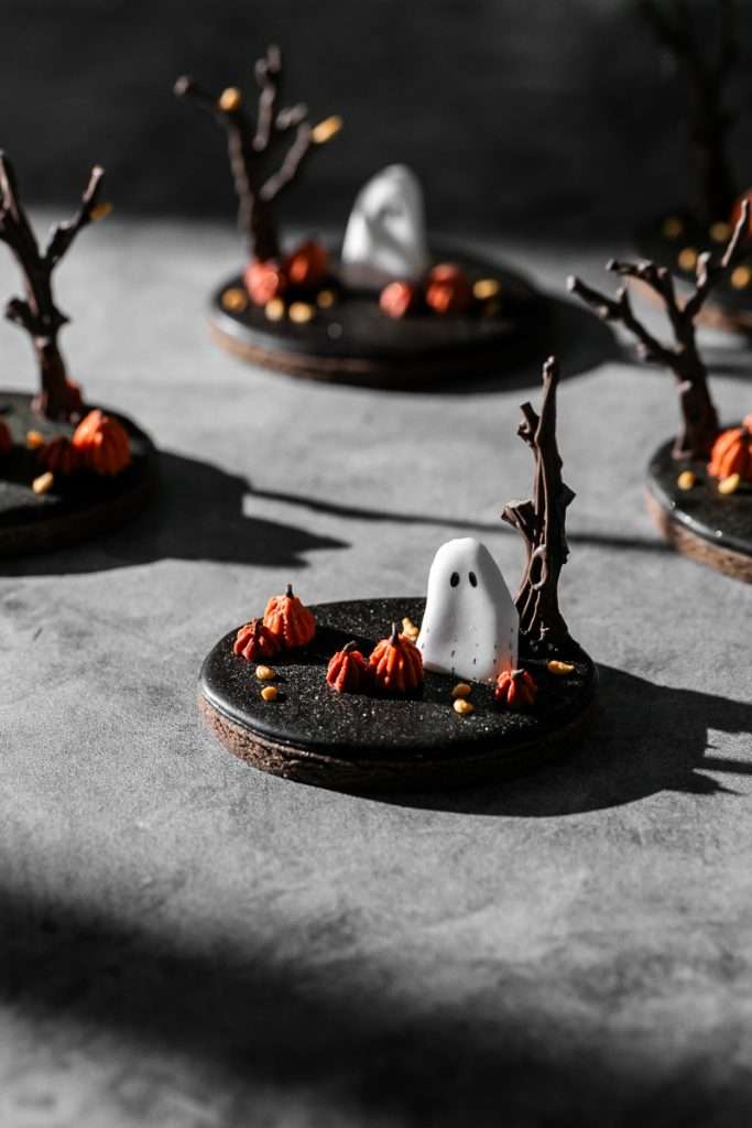 These spooky chocolate sugar cookies are decorated with rich chocolate royal icing and festive Halloween details. Featuring ghost icing transfers, they are not only delicious but perfect for dessert tables. cookie decorating inspiration and halloween themed parties.