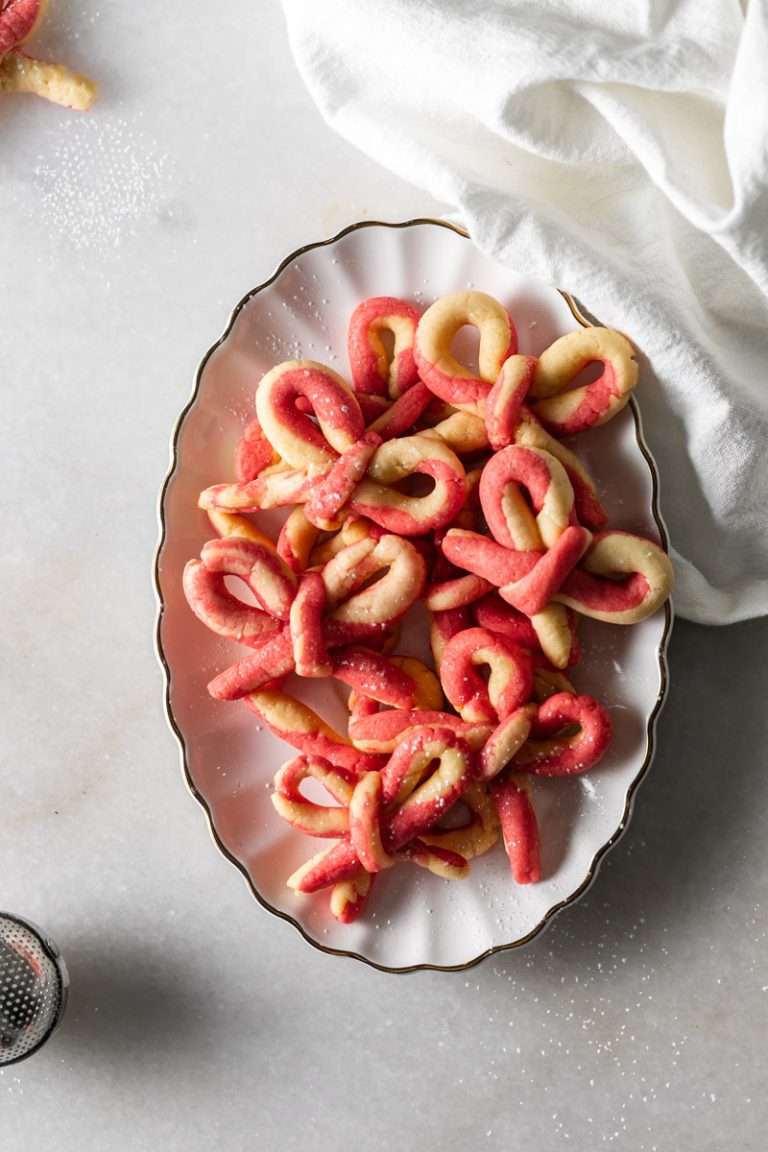 Peppermint infused candy cane bow sugar cookies shaped and twisted into bows and arranged on a holiday themed surface.